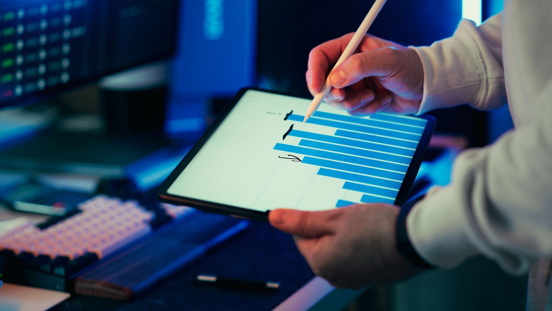 A professional analyzing a blue bar chart on a tablet screen with a stylus.