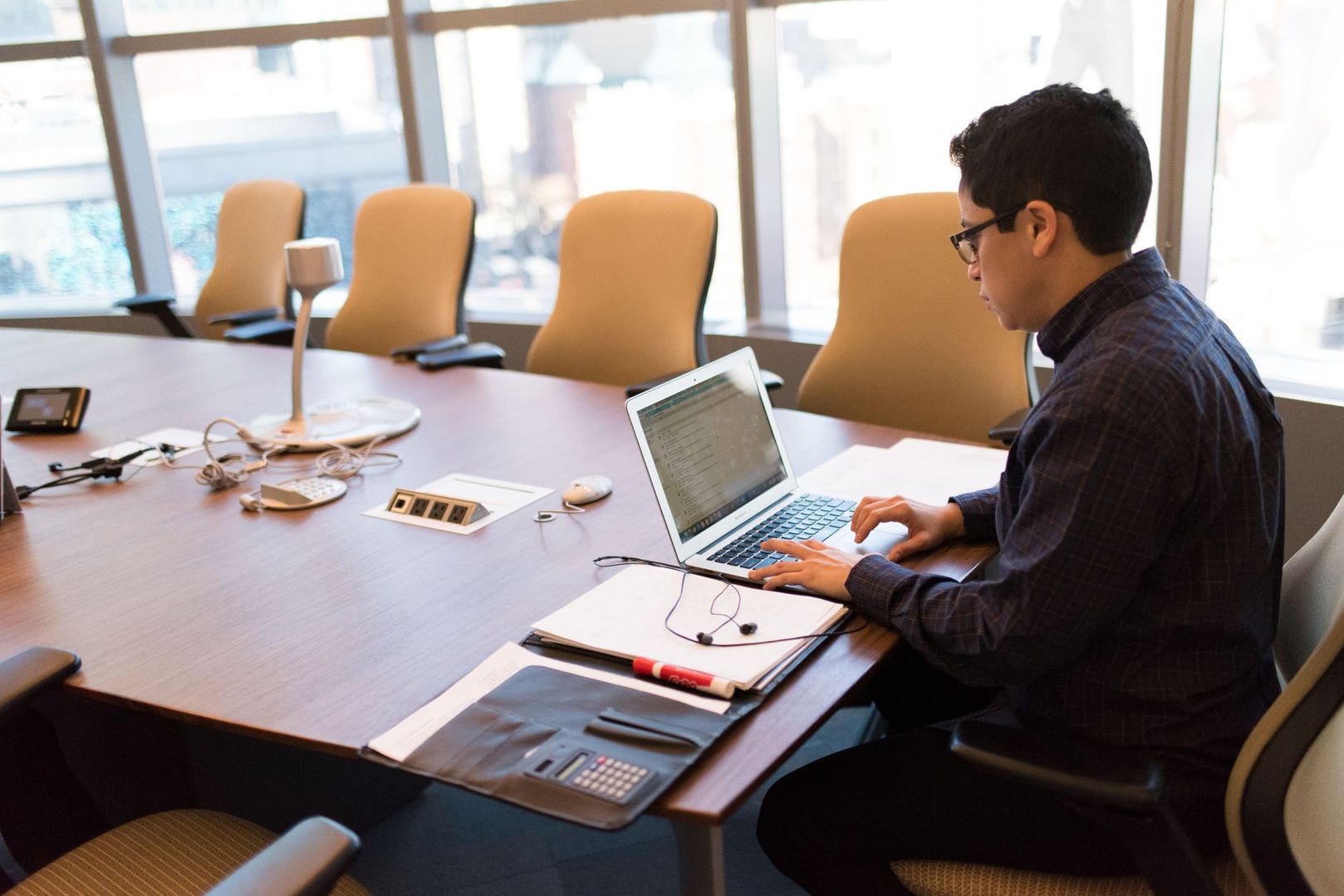 An employee works on a laptop in a modern conference room.