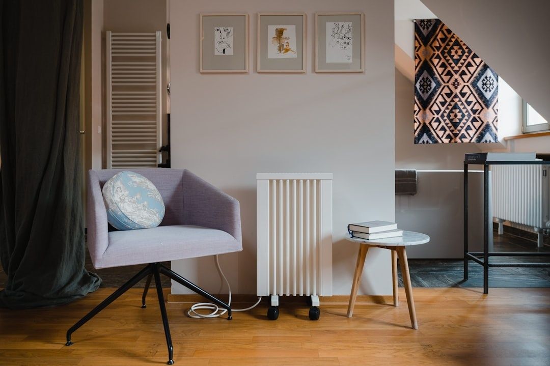 Cozy reading corner with armchair, side table, radiator, and framed art