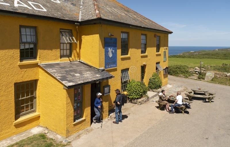 Historic yellow coastal inn with visitors and picnic tables outside